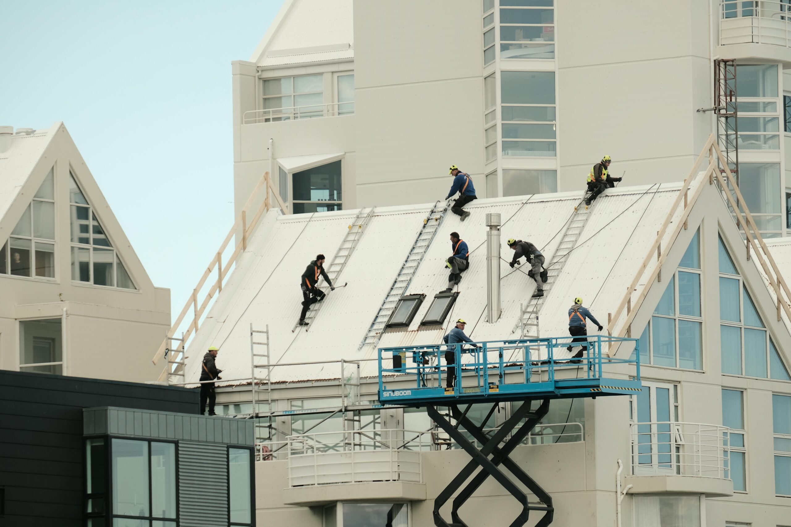 Construction workers repairing a modern roof in Reykjavík, highlighting teamwork and safety.